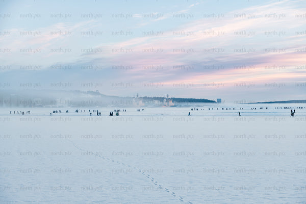 People on frozen sea at sunrise, winter