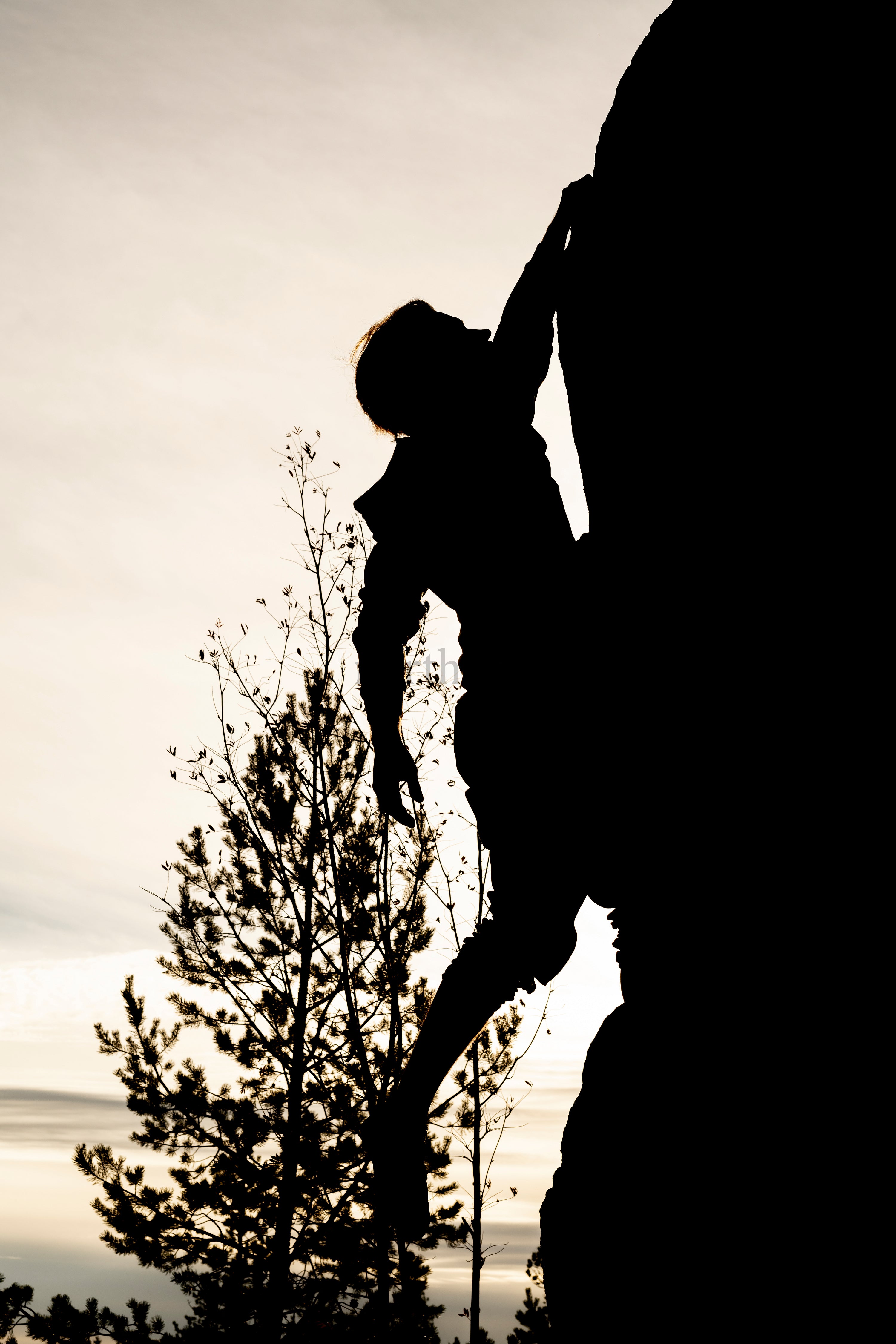 Silhouette of climber on rock face at sunset