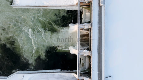 Hydroelectric Power Station Dam in Winter: An Aerial View of Flowing Water and Snow