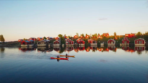 Kajakpaddling i Luleå skärgård i solnedgången med röda stugor: En sommardrönarvy