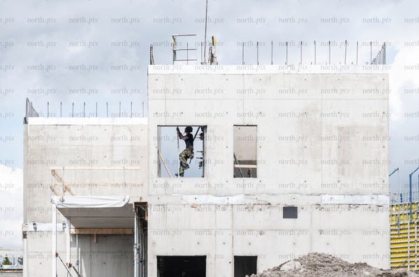 Construction worker in window opening on concrete building, daytime