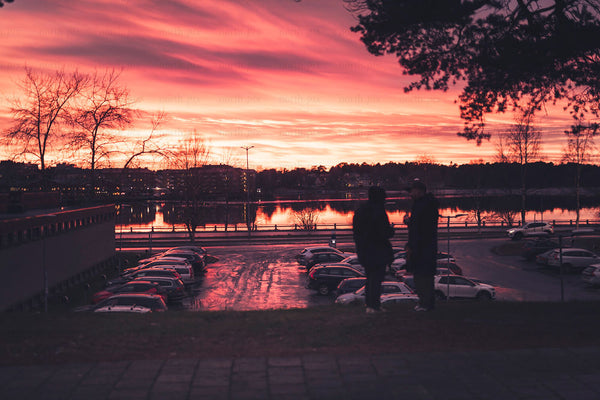 Two people silhouette by waterfront at sunset