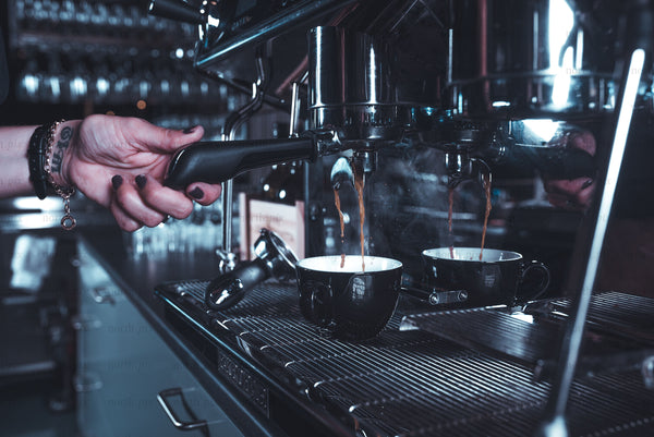 Barista pulling espresso shots at a commercial espresso machine