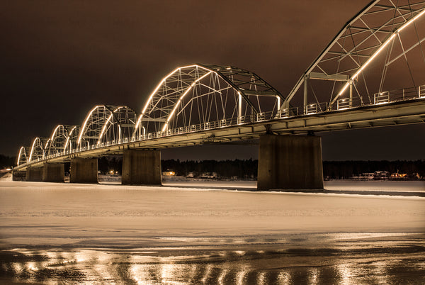 Illuminated arched bridge over frozen river at night