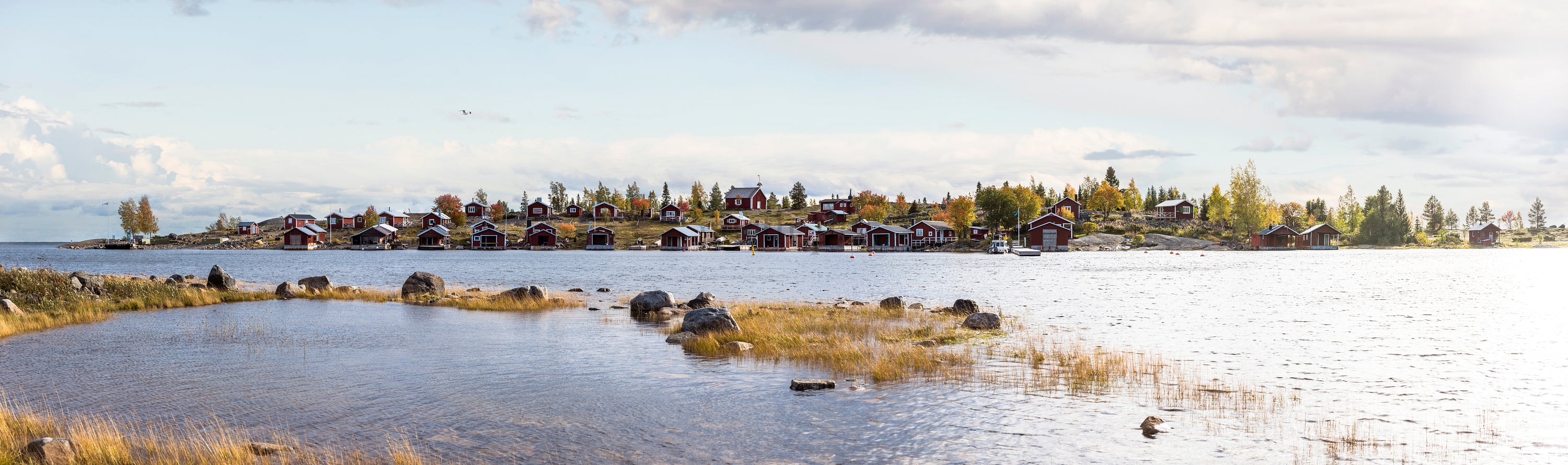 Red cottages along rocky shoreline in autumn