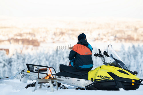 Person on snowmobile overlooking snowy forest in winter morning