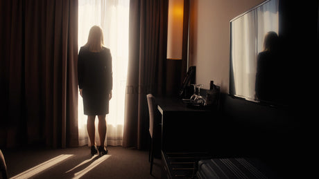 Businesswoman Opens Curtains to Sunrise View in Modern Hotel Room