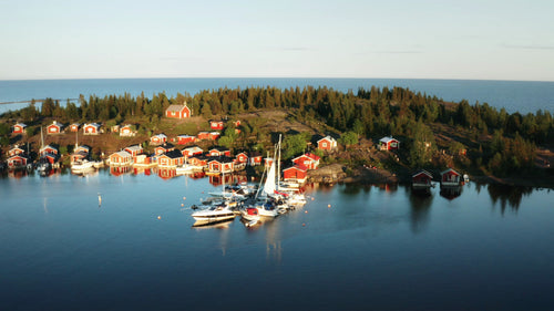 Sommarsolnedgång över Brandö skärgård: Röda stugor och båtar i svenska havet