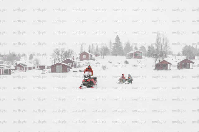 Snowmobile towing sled across frozen lake in winter
