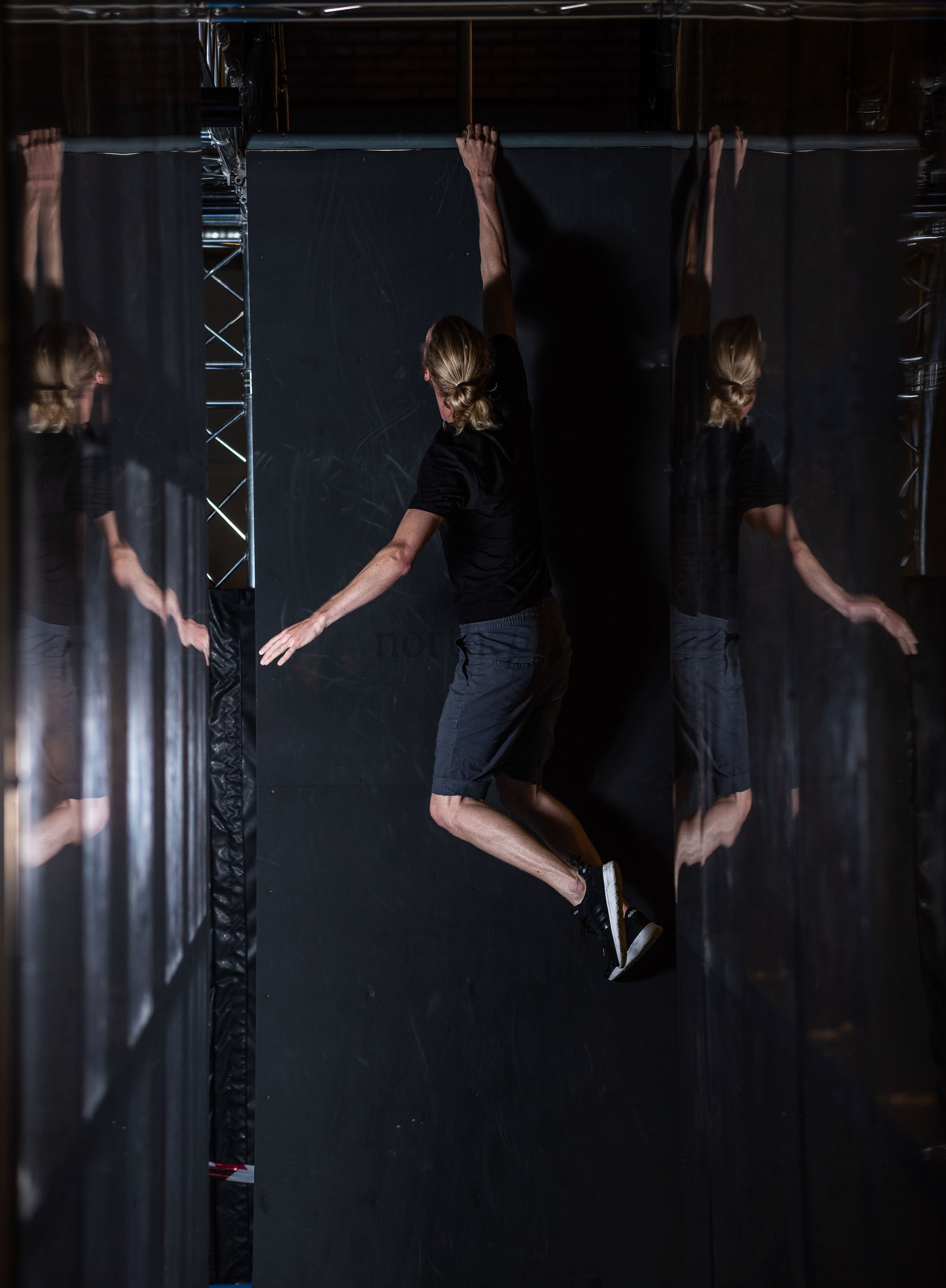 Person hanging from indoor wall with mirrored panels