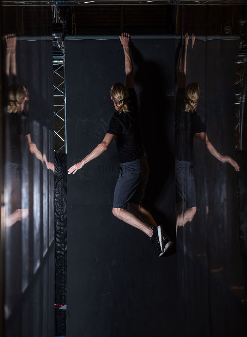 Person hanging from indoor wall with mirrored panels