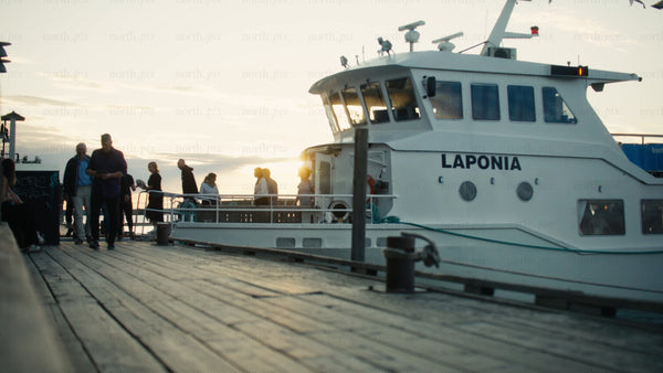 Urban summer evening: Passengers boarding tour boat at sunset in Luleå