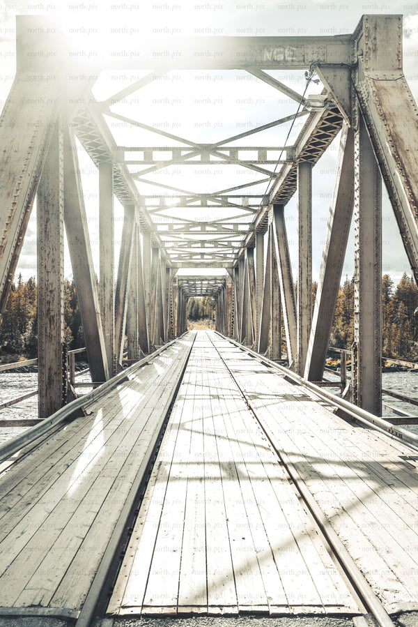 Metal truss bridge with wooden deck over river