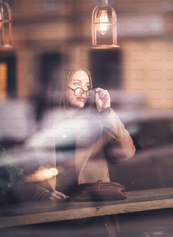 Woman looking out café window in evening light