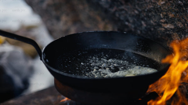 Frying potatoes over open fire in winter landscape, Luleå