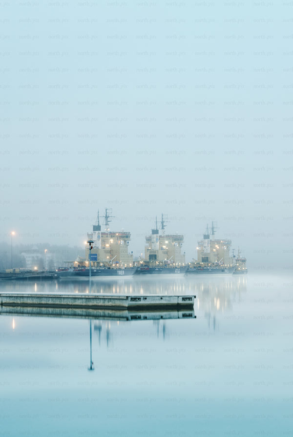 Three icebreakers docked at harbor in fog