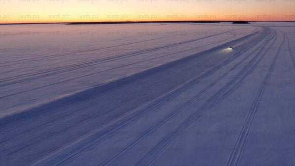 Car driving on ice road at sunset in Luleå archipelago – aerial view