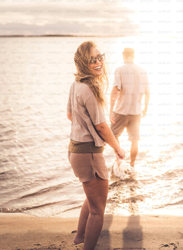 Woman smiling on beach at sunset with companion