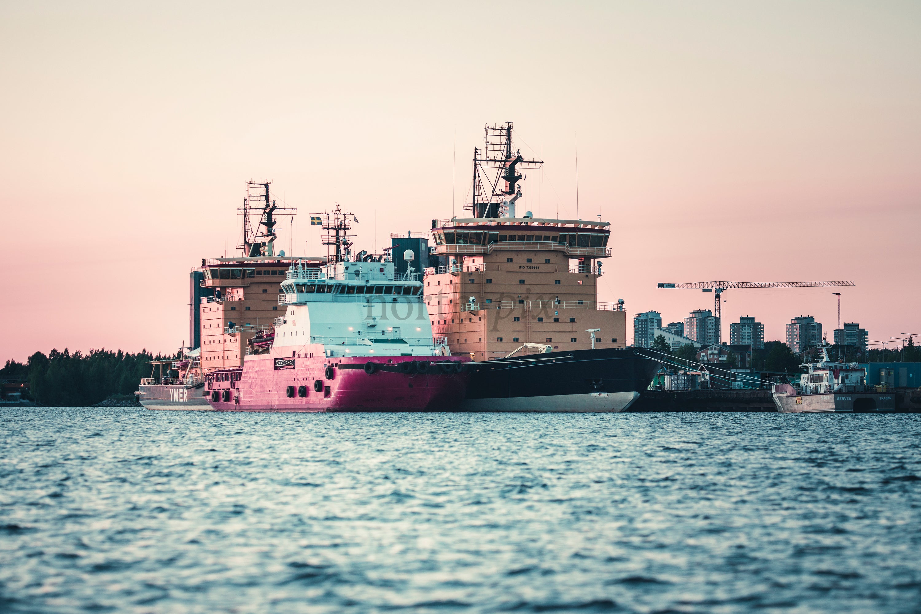 Ships docked at harbor at sunset