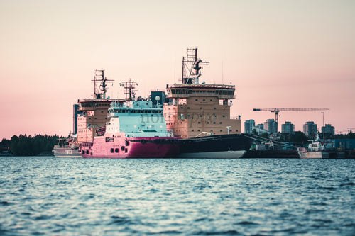 Ships docked at harbor at sunset
