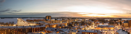 Snowy Winter City Panorama At Sunset With Illuminated Buildings And Waterfront Skyline