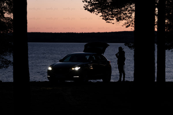Car and person by lake at dusk