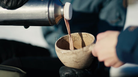 Pouring a Hot Drink into a Kuksa Mug in the Winter Luleå Archipelago, Sweden