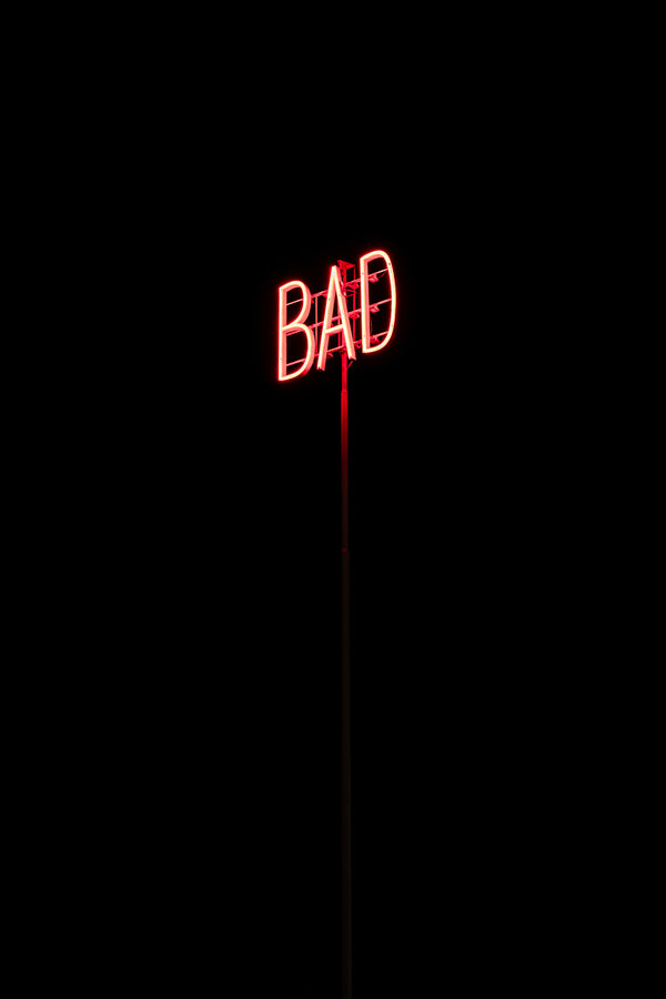 Red neon sign reading BAD on pole at night