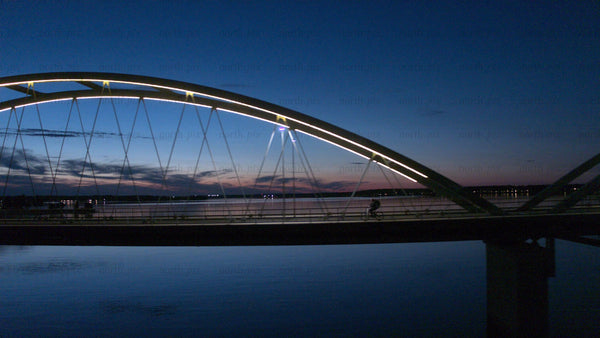 Cyclist crossing illuminated bridge in Luleå at twilight