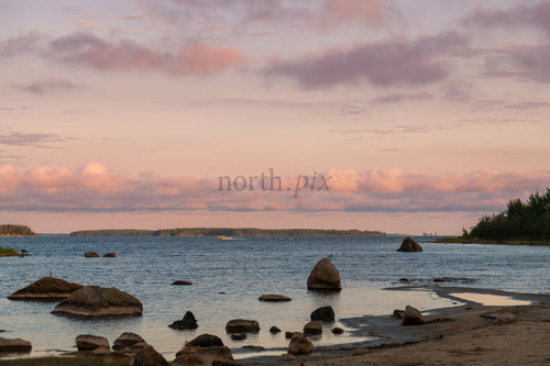 Rocky shoreline with islands and pink clouds at sunset