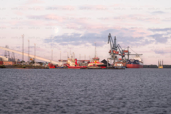 Cargo ship and cranes at industrial harbor at dusk