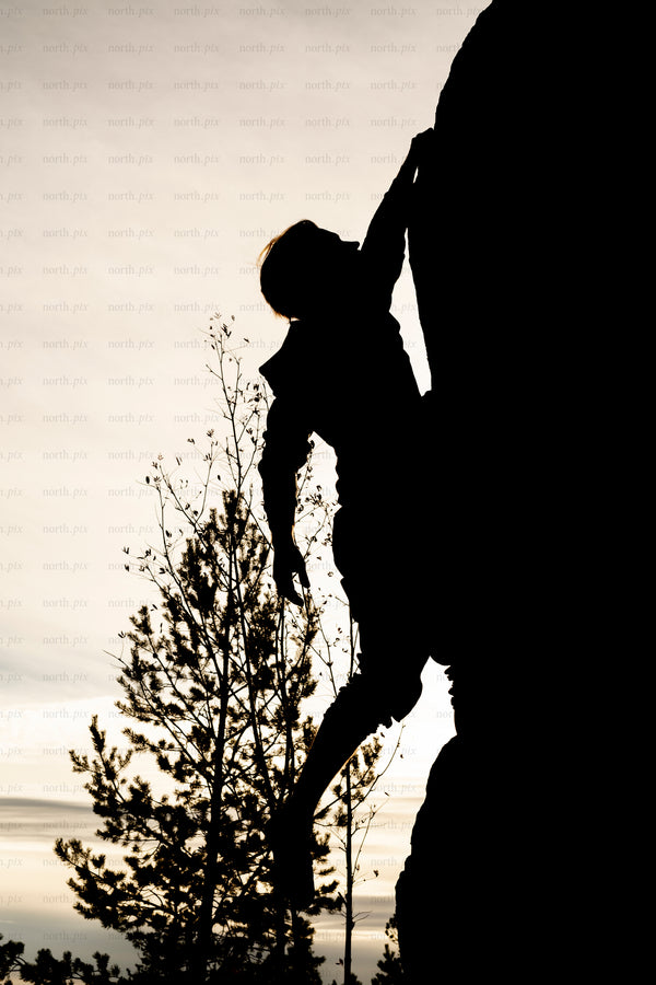 Silhouette of climber on rock face at sunset