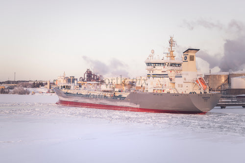 Cargo ship in icy harbor at sunrise