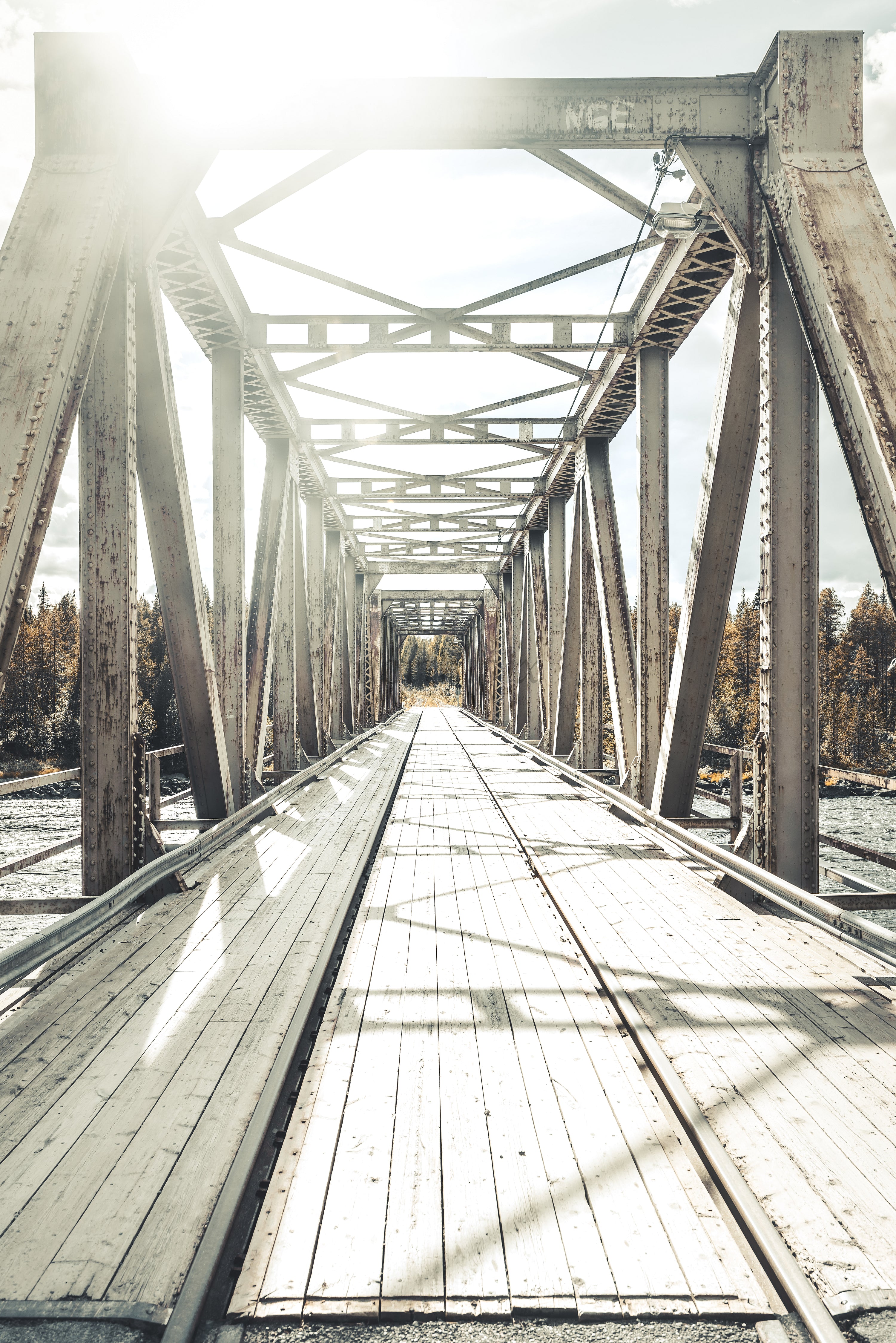 Metal truss bridge with wooden deck over river