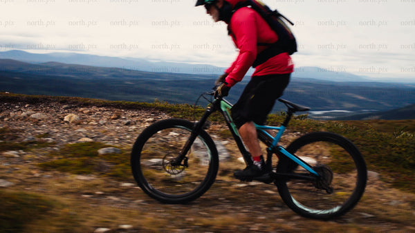 Mountain biker rides downhill on a rugged mountain trail