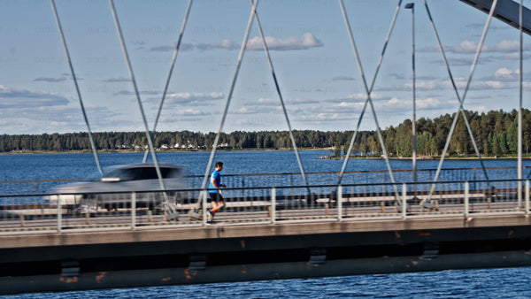 Man jogging across Bergnäsbron bridge in Luleå, on a sunny summer day