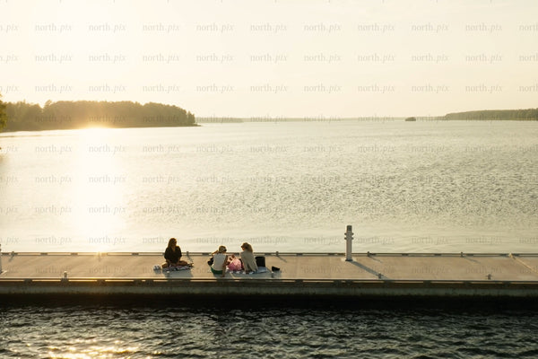 Sunset at calm lake dock with friends and family relaxing on a wooden pier