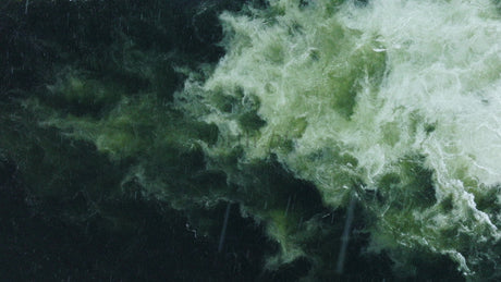 Top Down Aerial View of Swirling Water Flow With Teal and Green in the Rain