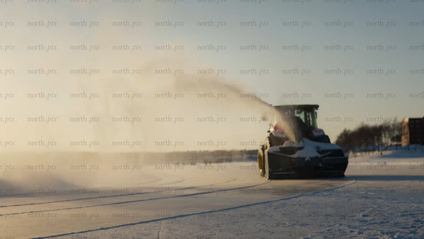 Snow blower tractor clearing frozen lake in Luleå, on a bright winter day