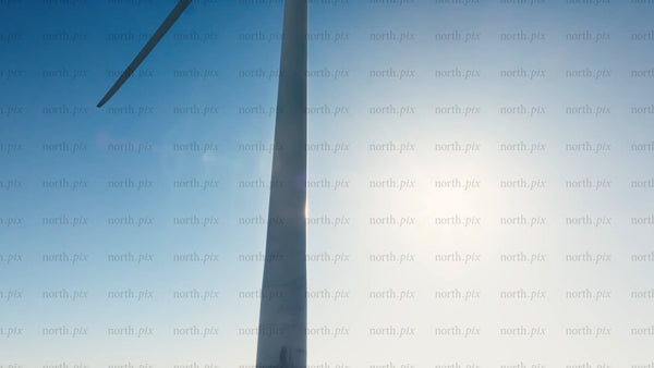 Rotating wind turbine against blue sky and sun: Zoom out to snowy winter landscape of Markbygden wind farm, Sweden