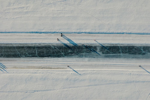 Flygfoto över snötäckt kanal i Luleå centrum med åkare och långa skuggor