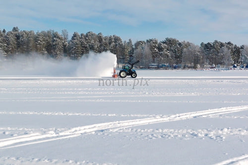 Vintersnöfält med traktor som röjer snö på frusen sjö nära Luleå centrum