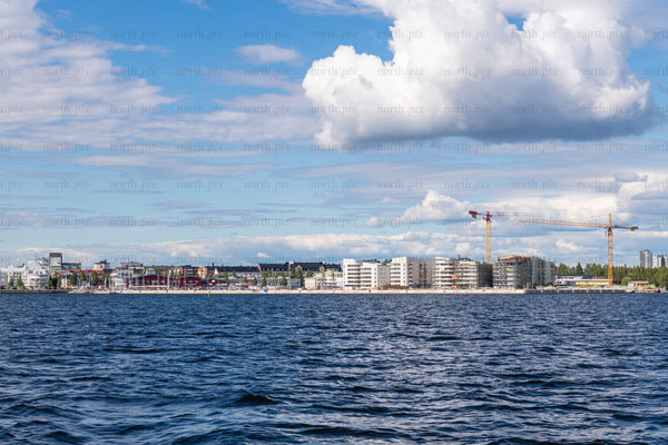 Waterfront city skyline with construction cranes at daytime
