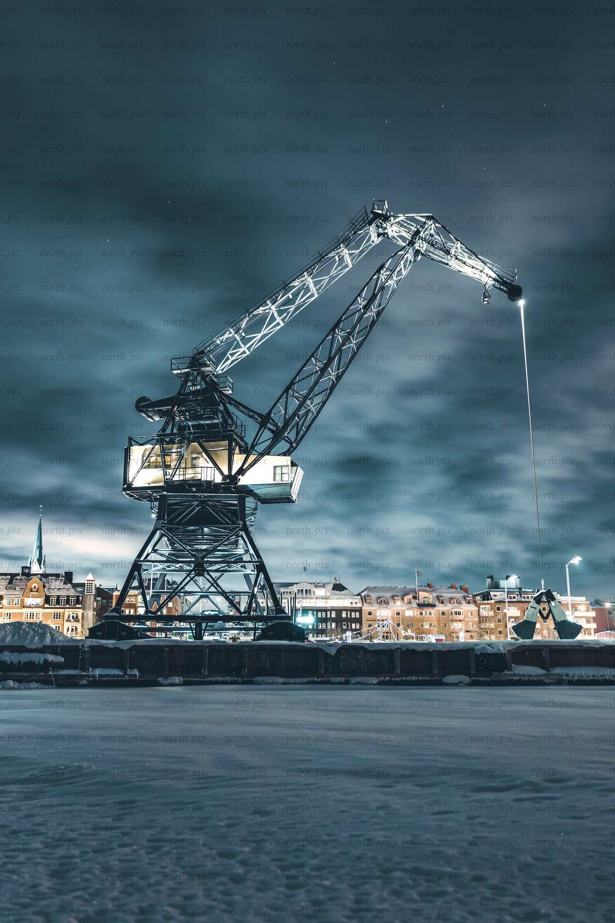 Luleå industrihamnskran på natten i snöig stad