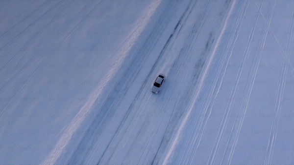 White car on a snowy ice road in Luleå during winter twilight
