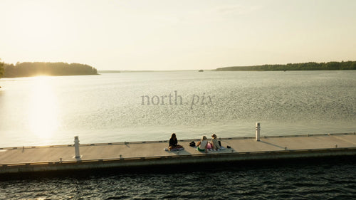 Vänner njuter av picknick i solnedgången på en pir i Luleå, Sverige