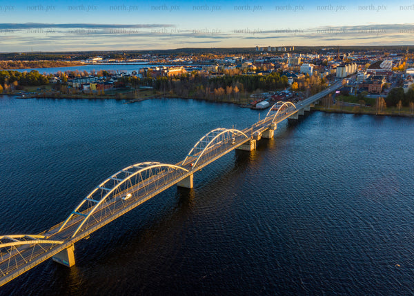 Aerial view of bridge over river during golden evening hour in Luleå