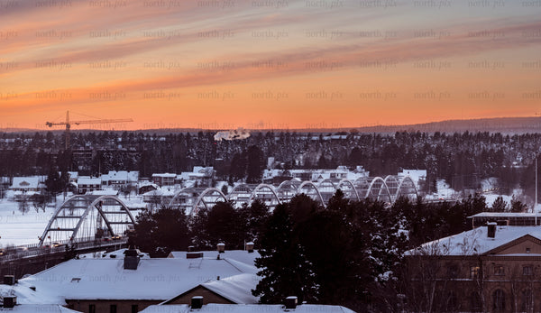 Arched bridge over snowy town at sunset