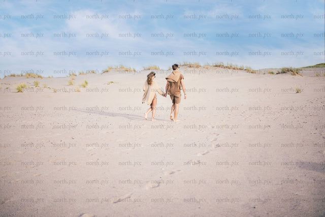 Couple walking on sand dunes at midday