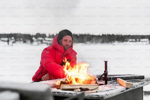 Man tending fire on frozen lake in winter
